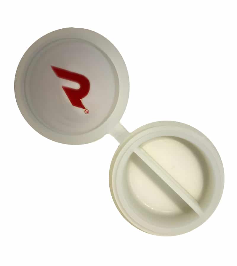 An open white plastic pill case has a red "R" logo on the lid and two compartments in the base.